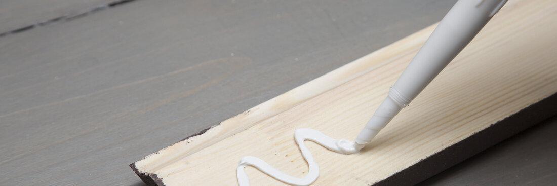 putting glue on a piece of wooden baseboard