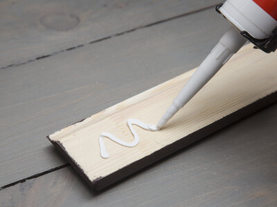 putting glue on a piece of wooden baseboard