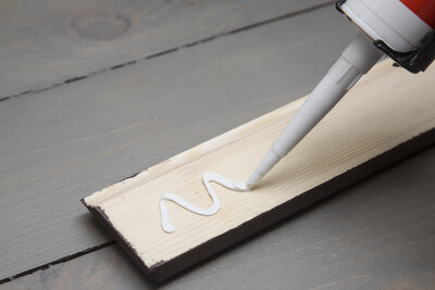 putting glue on a piece of wooden baseboard