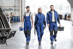 Drei Arbeiter mit Arbeitskleidung.