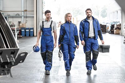Drei Arbeiter mit Arbeitskleidung.